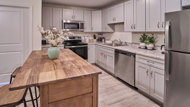 A modern kitchen with white cabinets, stainless steel appliances, and a wooden island. - Ruby 207: 1BD | Great LOCATION + Shared Amenities! (Pigeon Forge)