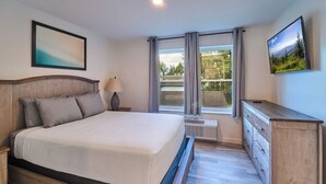 A bedroom with a bed, a nightstand, a lamp, a dresser, a TV, and a window with curtains. - Ruby 207: 1BD | Great LOCATION + Shared Amenities! (Pigeon Forge)