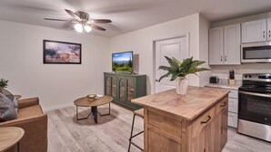 A modern kitchen with a central island, a dining area with a round table, and a ceiling fan. - Ruby 208: 1BD | Great LOCATION + Shared Amenities! (Pigeon Forge)