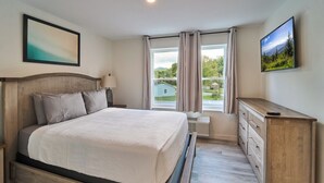 A bedroom with a bed, a nightstand, a dresser, and a window with curtains. - Ruby 208: 1BD | Great LOCATION + Shared Amenities! (Pigeon Forge)