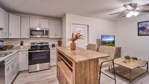 Une cuisine moderne avec des armoires blanches, des appareils en acier inoxydable et un îlot central en bois.