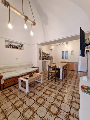A cozy living room with a sofa, coffee table, and patterned floor tiles.