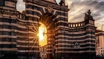 Ein großes, historisches Gebäude mit einem markanten Bogen und Statuen auf dem Dach.