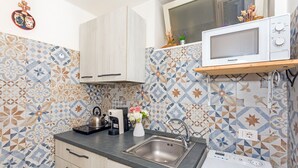 A kitchen with patterned tiles, a microwave, a sink, and a dishwasher.
