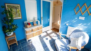 Une pièce avec un mur bleu, une porte blanche, un panier en osier, une chaise et un radiateur.