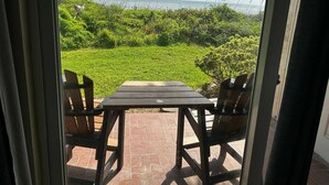 A patio with a wooden table and two chairs, overlooking a lush green landscape and the ocean. - Perfect located ocean front efficiency. (St. Augustine)