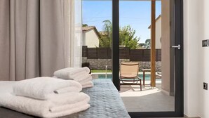 A hotel room with a bed, a chair, and a view of a swimming pool and outdoor area.