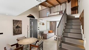 A spacious living area with a dining table and chairs, a sofa, and a staircase leading to an upper level. - Boutique suite Phos with BBQ next to Heraklion by Kalles Homes & Suites (Ano Kalesia)