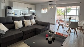 A modern living room with a sectional sofa, a glass coffee table, and a view of the kitchen and dining area. - House With Private Terrace, Sunsets and Barbeque (Arona)