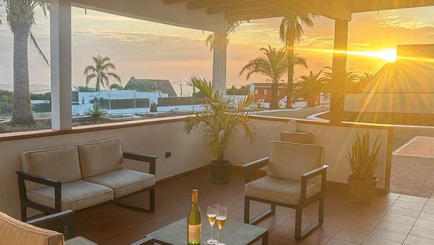 A covered outdoor seating area with sofas and a table, overlooking a sunset. - House With Private Terrace, Sunsets and Barbeque (Arona)