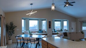A spacious kitchen with a large island, dining area, and seating by the windows. - Modern 4-bed home, 10 min from town. Deck with Aurora and mountain views, pond, updated kitchen, master suite with jet tub, radiant floors, fast Wi-Fi. Open concept living and dining. Beautifully renovated inside—cozy, private, and peaceful. (Fairbanks)