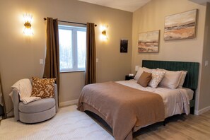 Un dormitorio con cama, una silla, un ventanal y luces en la pared.