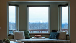A bay window with a view of a forested area. - Modern 4-bed home, 10 min from town. Deck with Aurora and mountain views, pond, updated kitchen, master suite with jet tub, radiant floors, fast Wi-Fi. Open concept living and dining. Beautifully renovated inside—cozy, private, and peaceful. (Fairbanks)
