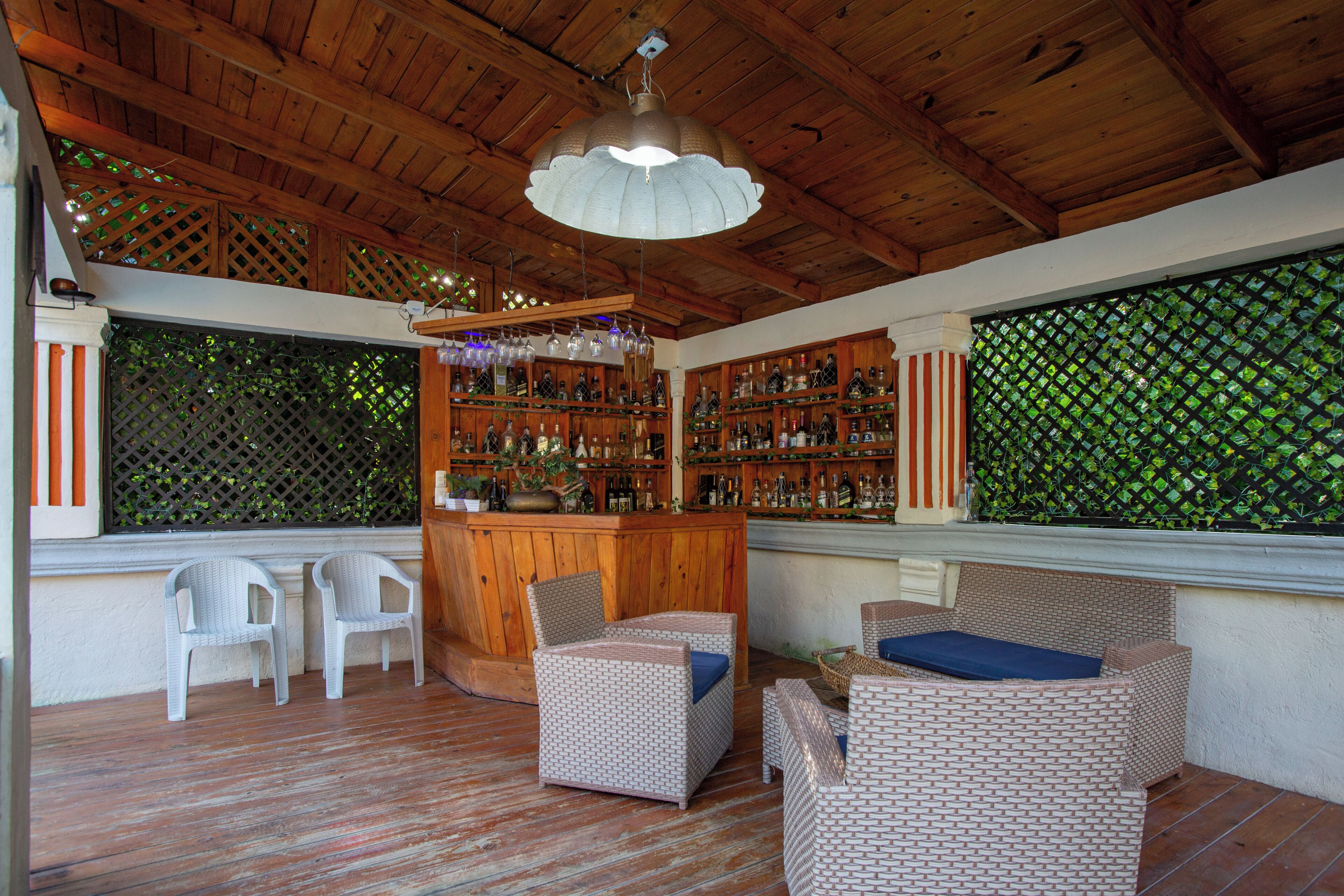 A wooden ceiling, wicker furniture, and a bar area with bottles.