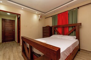A bedroom with a wooden bed frame, a nightstand, a dresser, and a door. - A 3-bedroom villa in beautiful San Francisco De Macoris with amenities and more (San Francisco De Macoris)