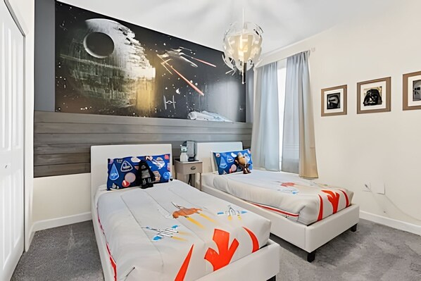 A hotel room with two beds, a large wall mural, a chandelier, and framed pictures on the wall.