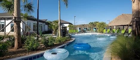 Piscina cercada por palmeiras e edifícios, com boias infláveis.