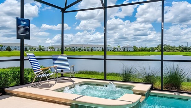 Un espace piscine comprenant deux chaises longues à rayures, un jacuzzi et une vue sur un terrain de golf et des bâtiments.