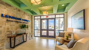 A lobby with a stone wall, a reception desk, a seating area, and a large window. - 6BR Townhome w/ Pool – 10 Min to Disney (Kissimmee)