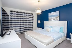 Een moderne slaapkamer met een groot bed, een nachtkastje, een lamp en een schilderij aan de muur.