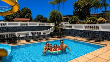 A swimming pool with lounge chairs and a water slide.