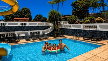 Una piscina con sillas de descanso y un tobogán de agua.