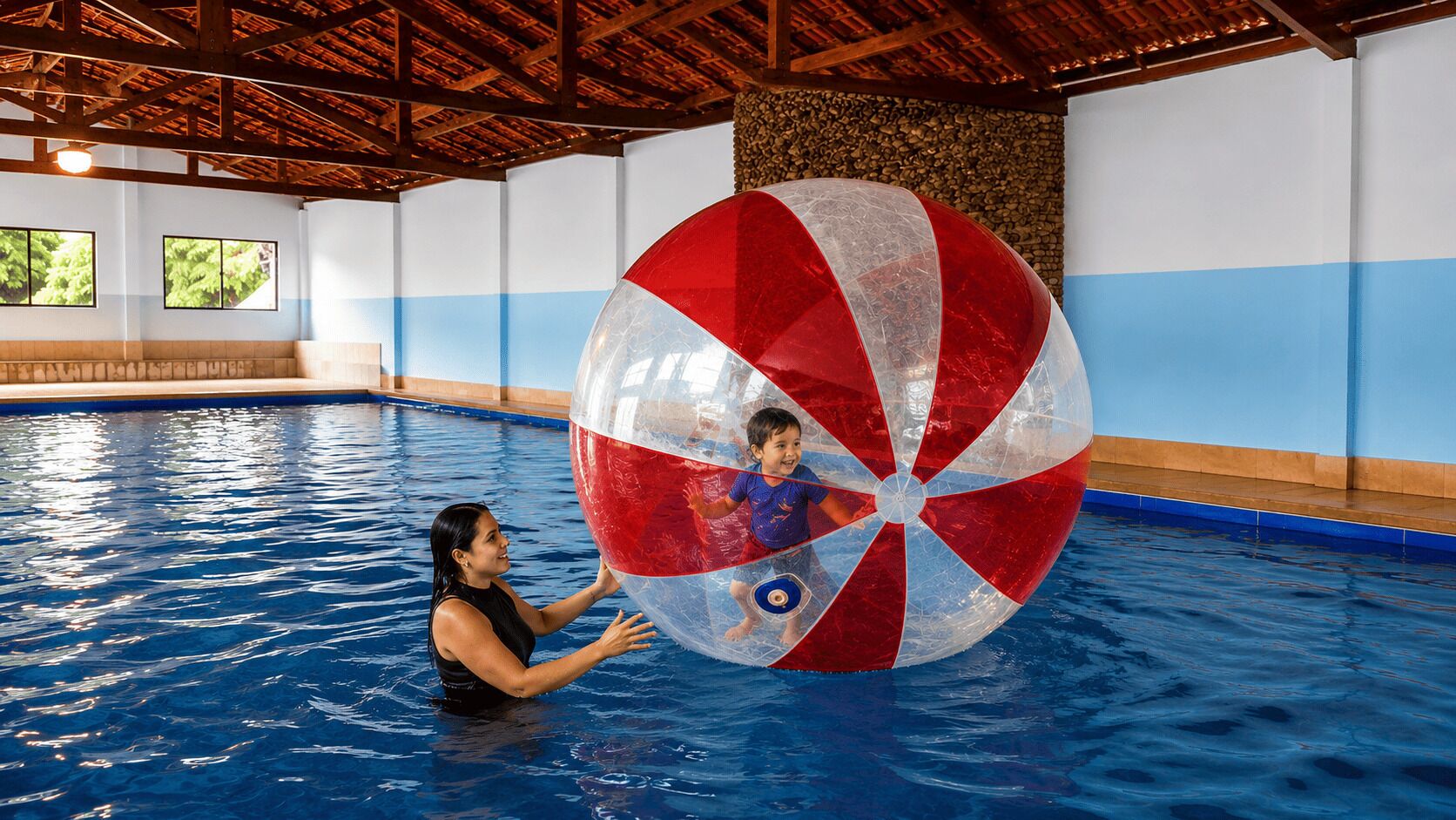 An indoor swimming pool with a large inflatable ball and a person.