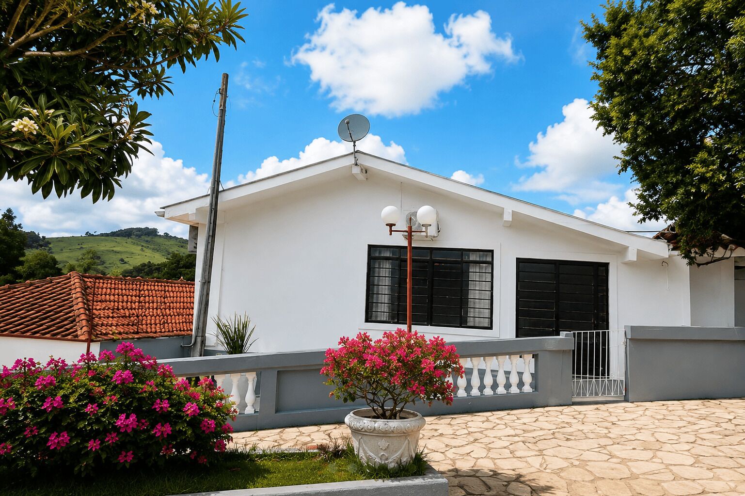 Um edifício branco com antena parabólica, persianas pretas e entrada com calçada de pedra.