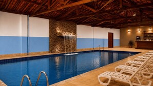 A swimming pool with a stone wall and a waterfall feature, surrounded by lounge chairs. - Hotel Fazenda Águas de Lindóia (Águas de Lindóia)