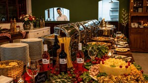A buffet table with various food items, wine bottles, and a television screen in the background. - Hotel Fazenda Águas de Lindóia (Águas de Lindóia)