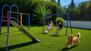 Un parque infantil con tobogán y columpios, rodeado por una zona vallada y vegetación.