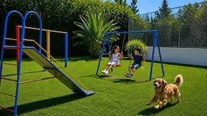 A playground with a slide and swings, surrounded by a fenced area and greenery. - Hotel Fazenda Águas de Lindóia (Águas de Lindóia)