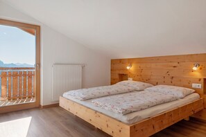 Een slaapkamer met een houten bed, uitzicht door een groot raam en een houten plafond.