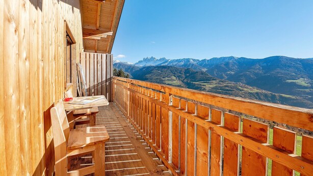 A wooden balcony with a view of mountains.