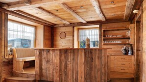 A wooden interior with a bar area, a window with a view, and a shelf with glasses.