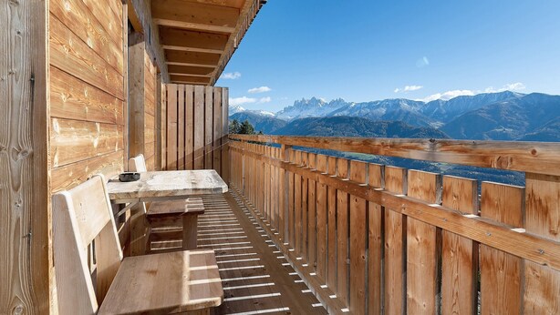 Ein Holzbalkon mit Blick auf schneebedeckte Berge.