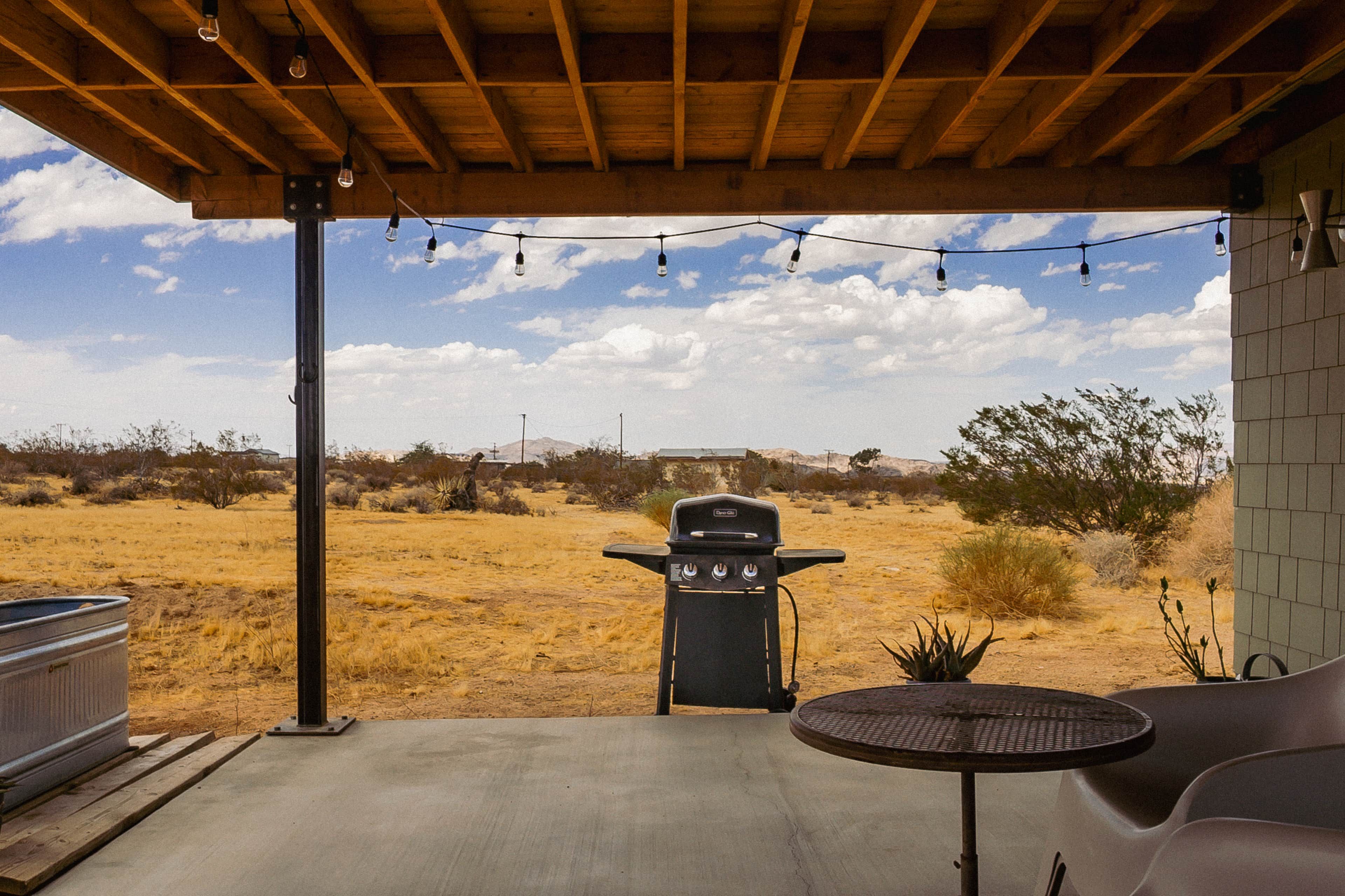 An outdoor patio with a barbecue grill, a table, and chairs.