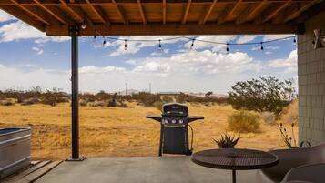An outdoor patio with a barbecue grill, a table, and chairs.