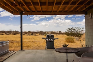 An outdoor patio with a barbecue grill, a table, and chairs.