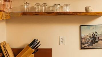 A kitchen with wooden shelves holding various glassware and a knife block.