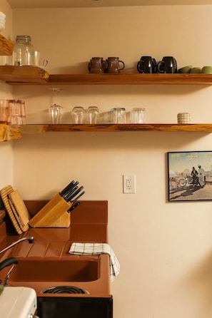A kitchen with wooden shelves holding various glassware and a knife block.