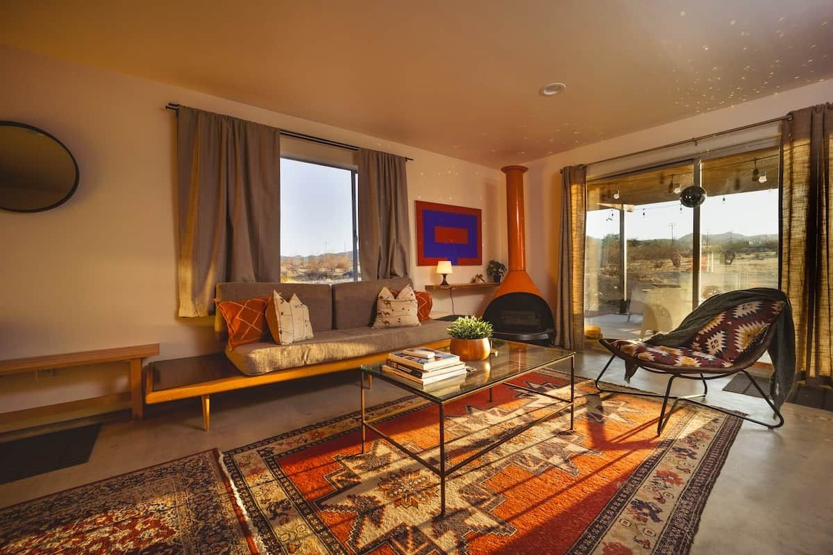 A living room with a sofa, a coffee table, a patterned rug, a chair, and a fireplace.