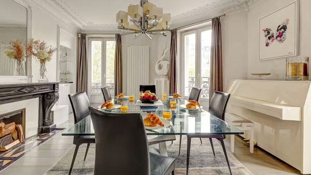 A dining room with a glass table, black chairs, a chandelier, and a piano. - NEW: Stunning spacious flat in Champs-Elysees (Paris)