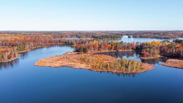 A serene lake surrounded by autumn-colored trees and a clear sky.