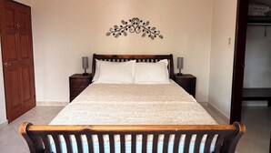 A bedroom with a wooden bed, a ceiling fan, a decorative wall piece, and a wardrobe. - Marvelous 3-bedroom Apartment in Villa, Beautiful Pool, Steps from Surf & Ocean (Atlantic Shores)