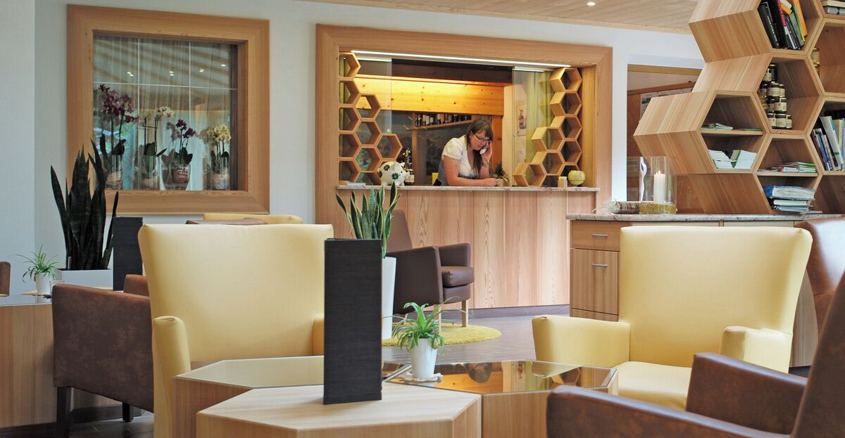 A modern lobby with a reception desk, seating area, and a bookshelf.