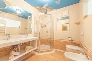 Un baño con ducha de vidrio, lavamanos, inodoro y espejo.