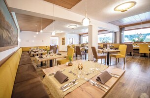 Un restaurante con varias mesas y cabinas, suelo de madera e iluminación colgante.