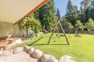 Un patio trasero con un columpio, una mesa de picnic y un área de juegos cercada.