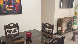 A dining area with a wooden table and chairs, a red candle, and a painting on the wall.